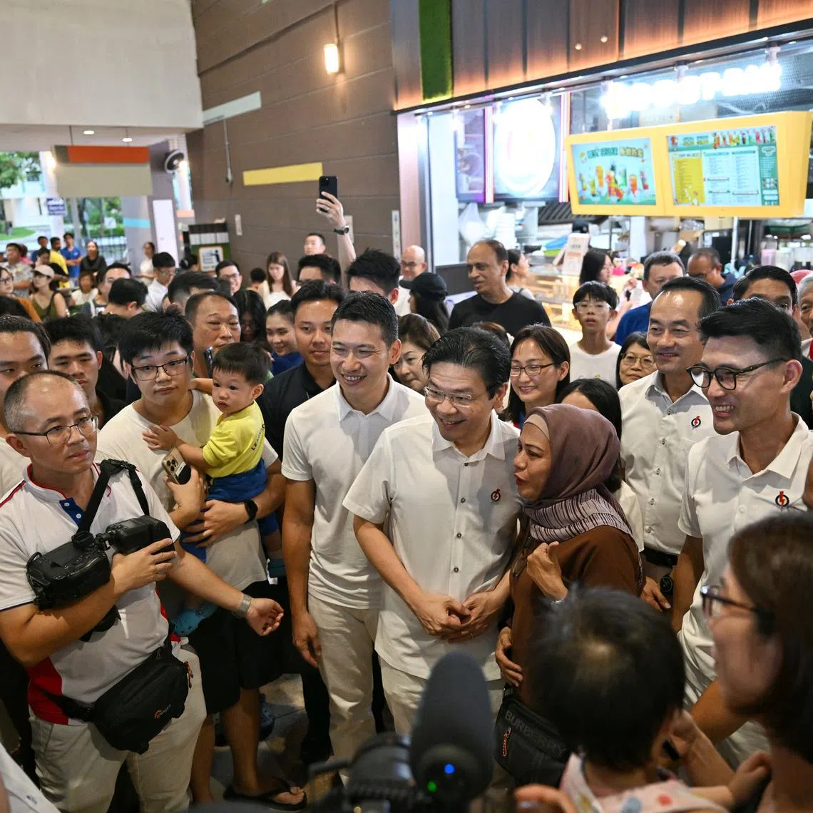 PM Lawrence Wong and the PAP's Tampines GRC candidates posing for photos with residents during a walkabout on April 30.