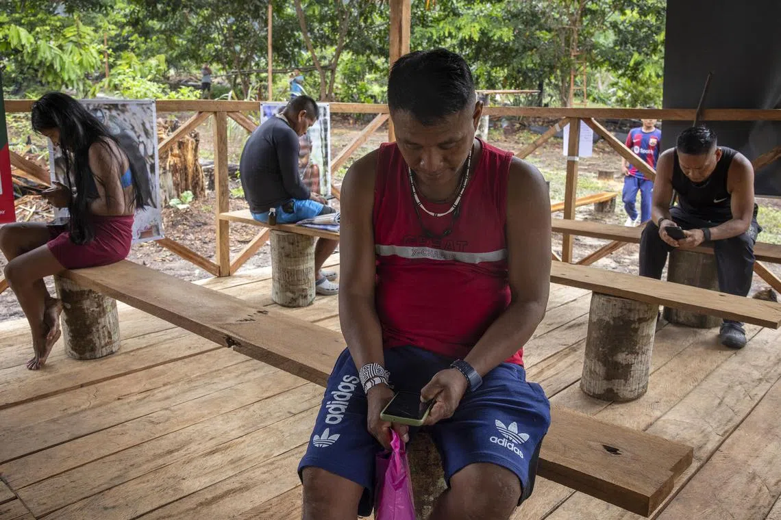 Marubo people use their phones, bought in the closest city, when the Starlink antenna is turned on in their village, in Manakieaway, a Marubo village in Brazil’s Acre state on April 8, 2024. 