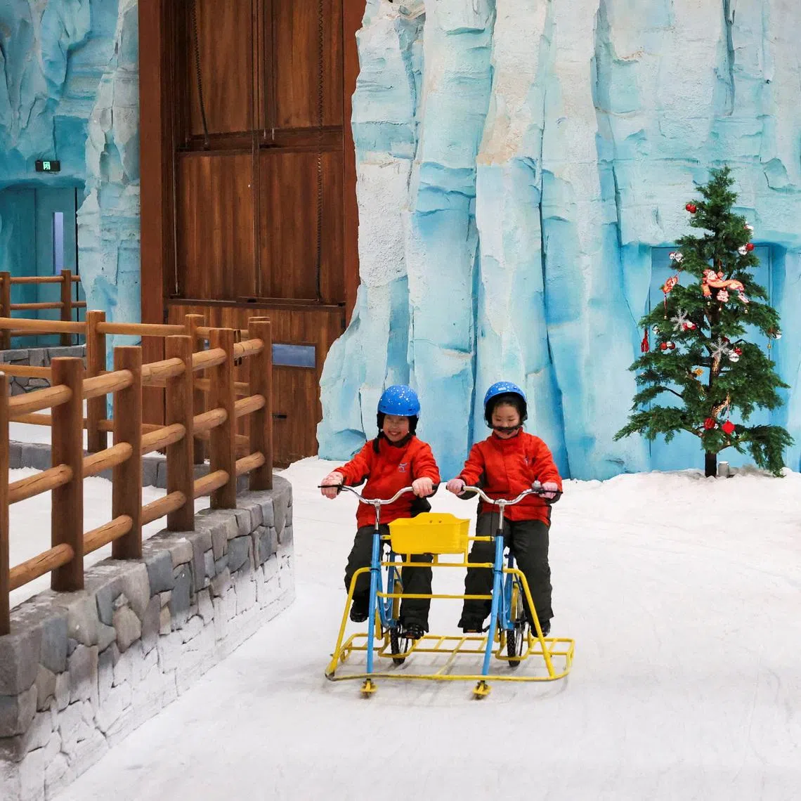 FILE PHOTO: Children ride a snow bicycle at Shanghai L+SNOW Indoor Skiing Theme Resort amid an orange alert for heat in Shanghai, China August 28, 2025.