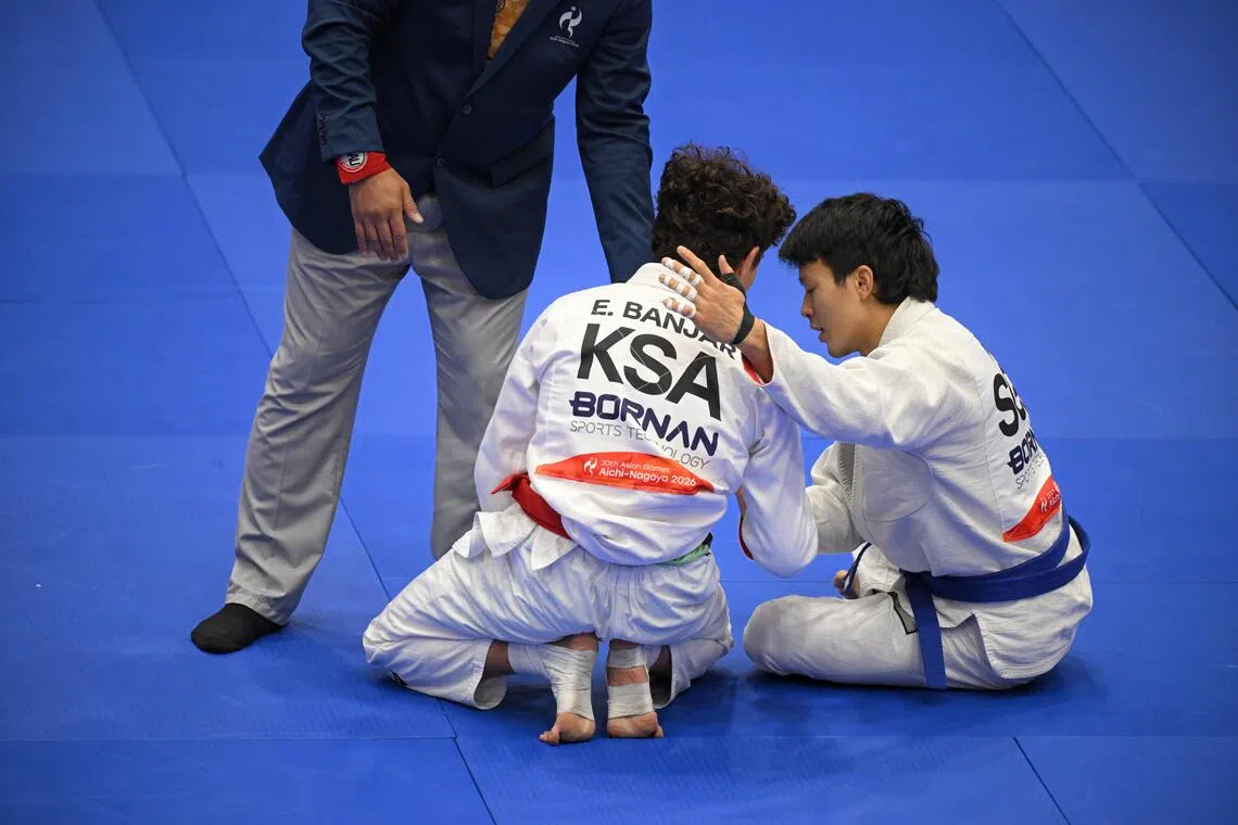 Singaporean jiu-jitsu fighter Noah Lim (right) sitting down and putting a consoling arm around his defeated and emotional rival Elyas Zwawi Y Banjar of Saudi Arabia at the Asian Games.