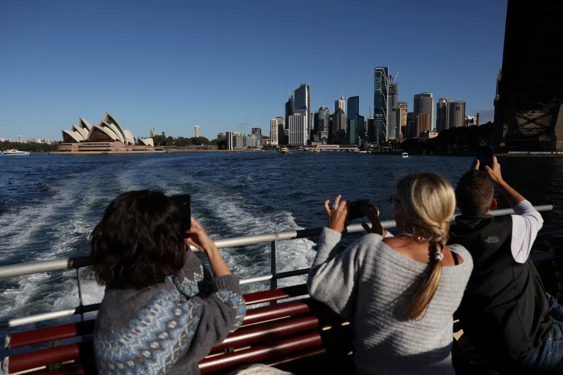 FILE PHOTO: People take photos of the Sydney Opera House and Central Business District (CBD) skyline in Sydney, Australia, July 9, 2025. REUTERS/Hollie Adams/ File Pjhoto