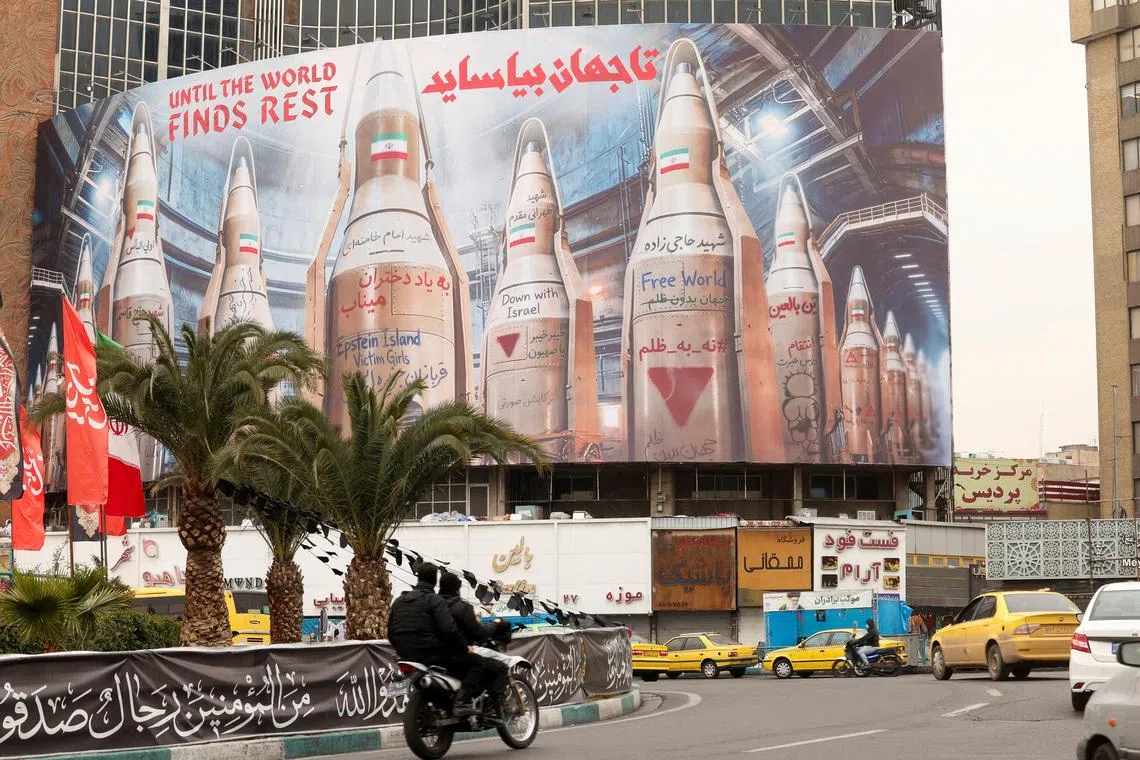 People on motorcycles ride past a large billboard with images of Iranian missiles, amid the U.S.-Israeli conflict with Iran, in Tehran, Iran, March 15, 2026. REUTERS/Alaa Al-Marjani