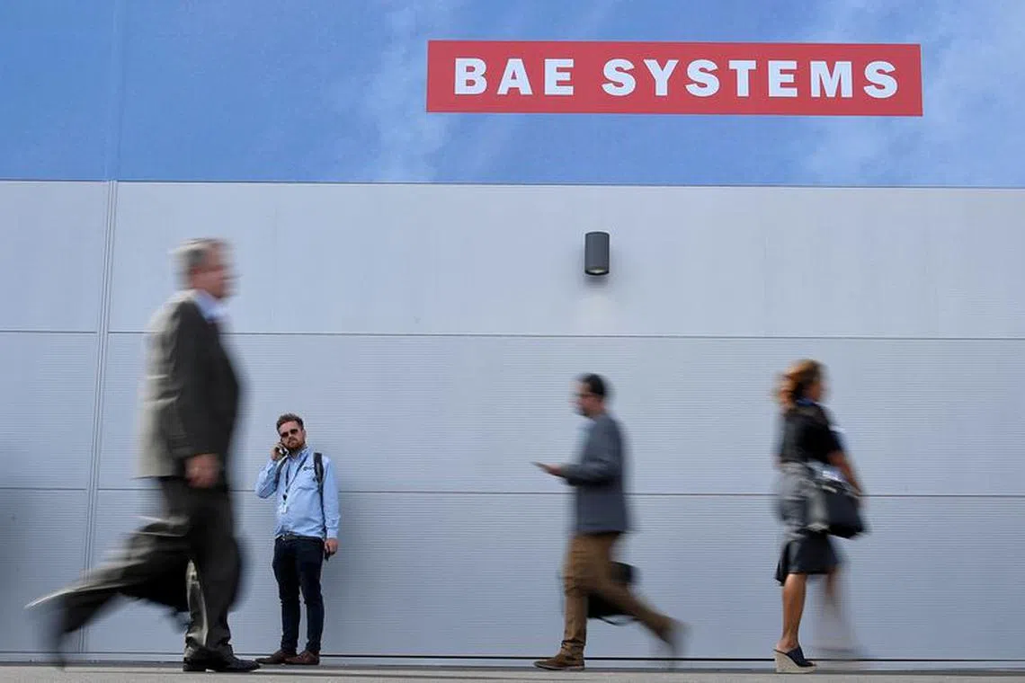 FILE PHOTO: Trade visitors walk past an advertisement for BAE Systems at Farnborough International Airshow in Farnborough, Britain, July 17, 2018. REUTERS/Toby Melville/File Photo