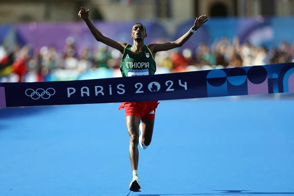Tamirat Tola of Ethiopia celebrates as he crosses the finish line at Invalides to win gold in the Paris Olympics men's marathon - on Aug 10, 2024..