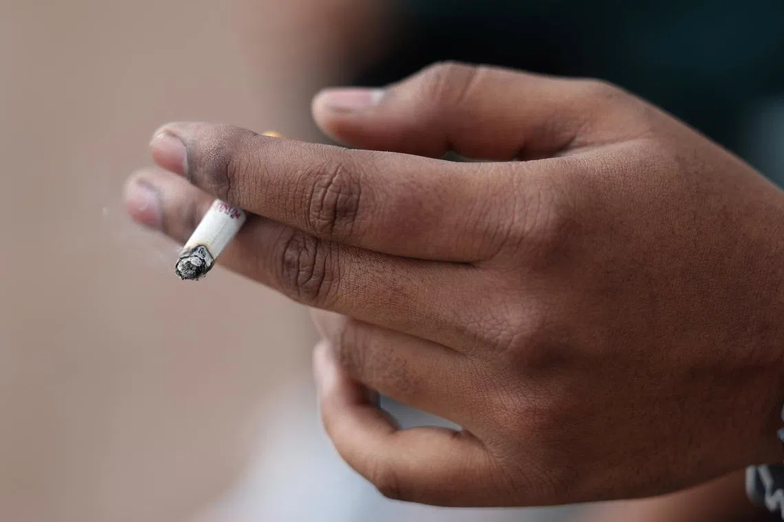 FILE PHOTO: A man holds his cigarette as he smokes in London, Britain, April 11, 2024. REUTERS/Isabel Infantes/File Photo