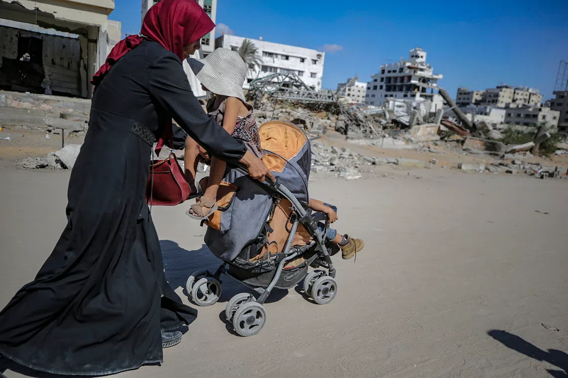 A Palestinian mother flees with her children following an Israeli airstrike during an Israeli military operation in Gaza City.