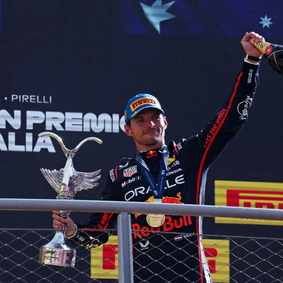 Red Bull's Max Verstappen celebrates with a trophy and champagne on the podium after winning the Italian Grand Prix.