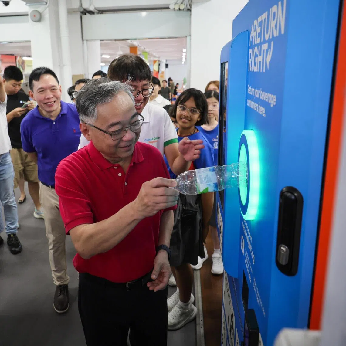 DPM Gan Kim Yong recycling a plastic bottle at a Return Right machine during a tour of exhibition booths at the launch of Go Green SG 2026 at Naval Base Primary School on May 11. 