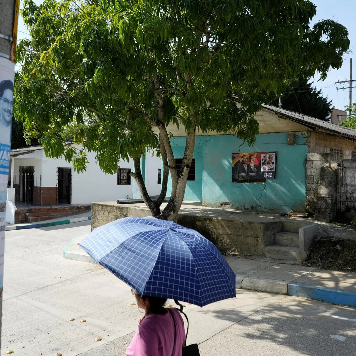 A woman walks past electoral advertisements ahead of the 21 June runoff between right-wing presidential candidate Abelardo De La Espriella and leftist candidate Ivan Cepeda, in Tubara, Colombia, June 10, 2026. REUTERS/Charlie Cordero