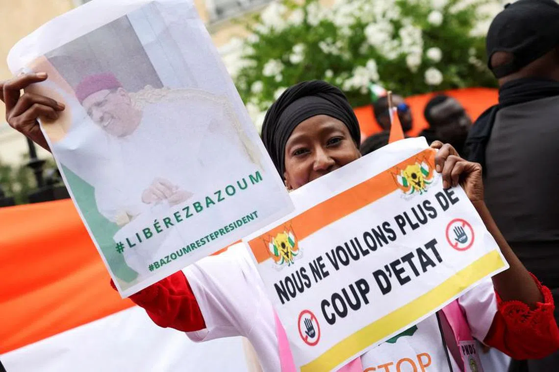 FILE PHOTO: A demonstrator holds placards, one of them reading \"We don't want a coup anymore\", outside Niger's embassy in support of the President of Niger Mohamed Bazoum in Paris, France, August 5, 2023. REUTERS/Stephanie Lecocq/File Photo