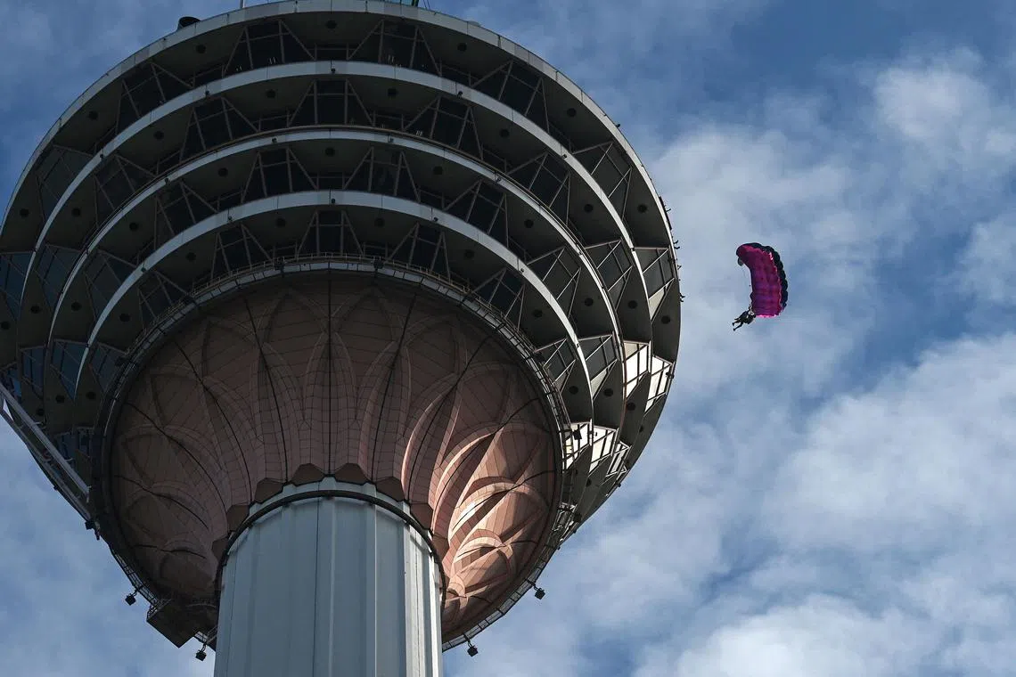Base jumpers leap from the 300-metre high open deck of Malaysia's landmark Kuala Lumpur Tower during the International Tower Jump in Kuala Lumpur on Feb 3, 2023. 