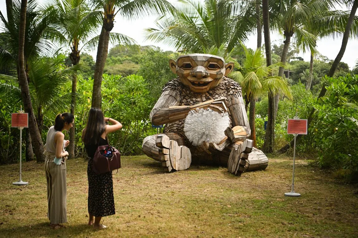 People taking photos of Little Lyn, one of four giant sculptures created by internationally renowned recycling artist Thomas Dambo along Palawan Beach at Sentosa island, Singapore, Dec 13, 2022. 