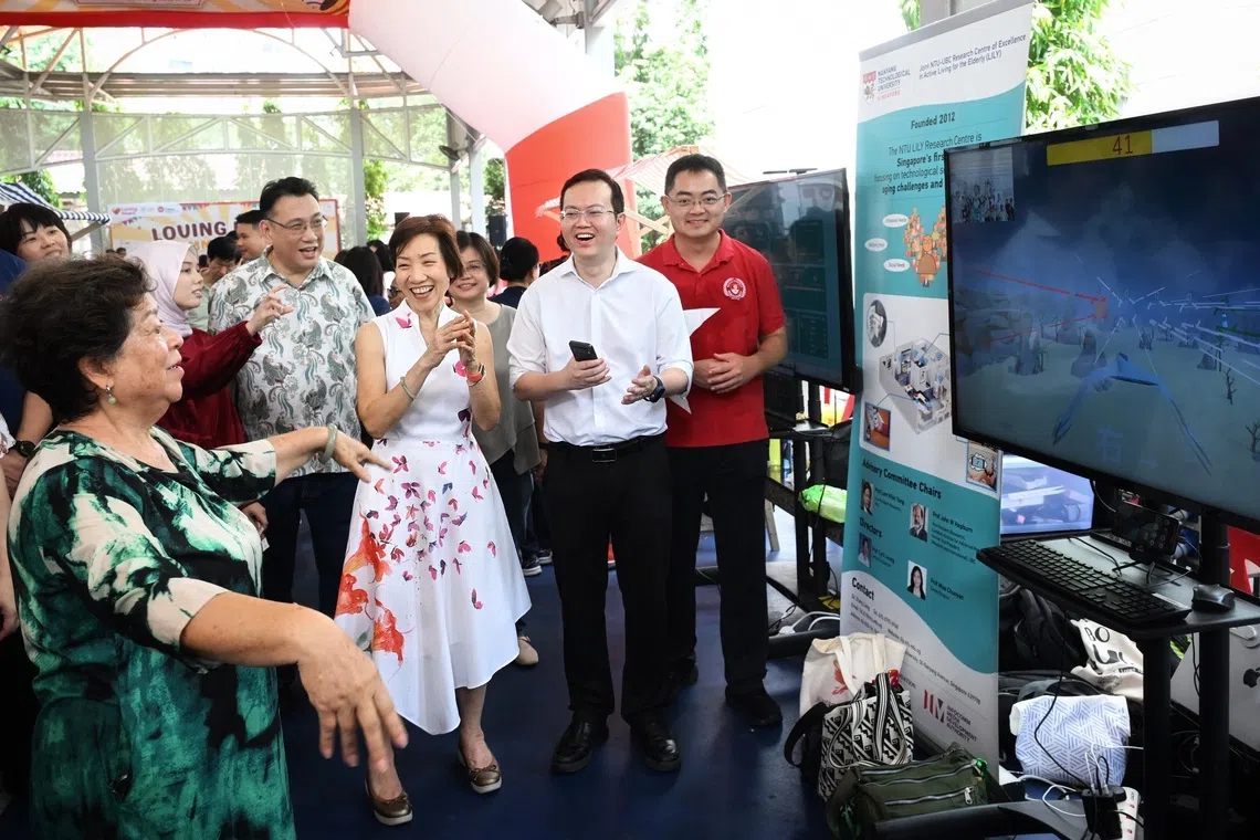 (From second far left) Kenny Teo, MD, Gain City; Minister for Sustainability and the Environment Grace Fu; and Dr Jedi Pan Zhengxiang, NTU LILY research scientist and programme director (Ageing Technology Engagement) supporting a resident at the Loving Heart Community Day on Aug 16.