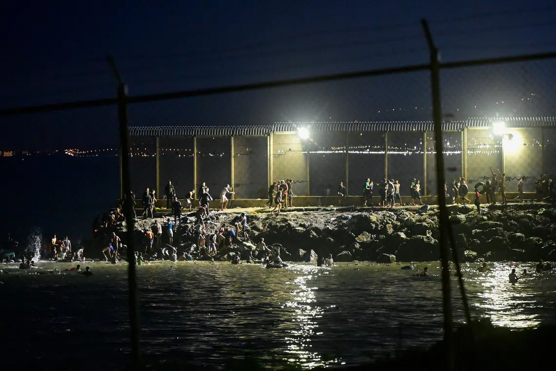 Migrants from Morocco cross into Ceuta by sea and gather near the border fence between the Spanish enclave of Ceuta and Morocco, as seen from Ceuta, Spain, July 30, 2026. REUTERS/Fabian Bimmer