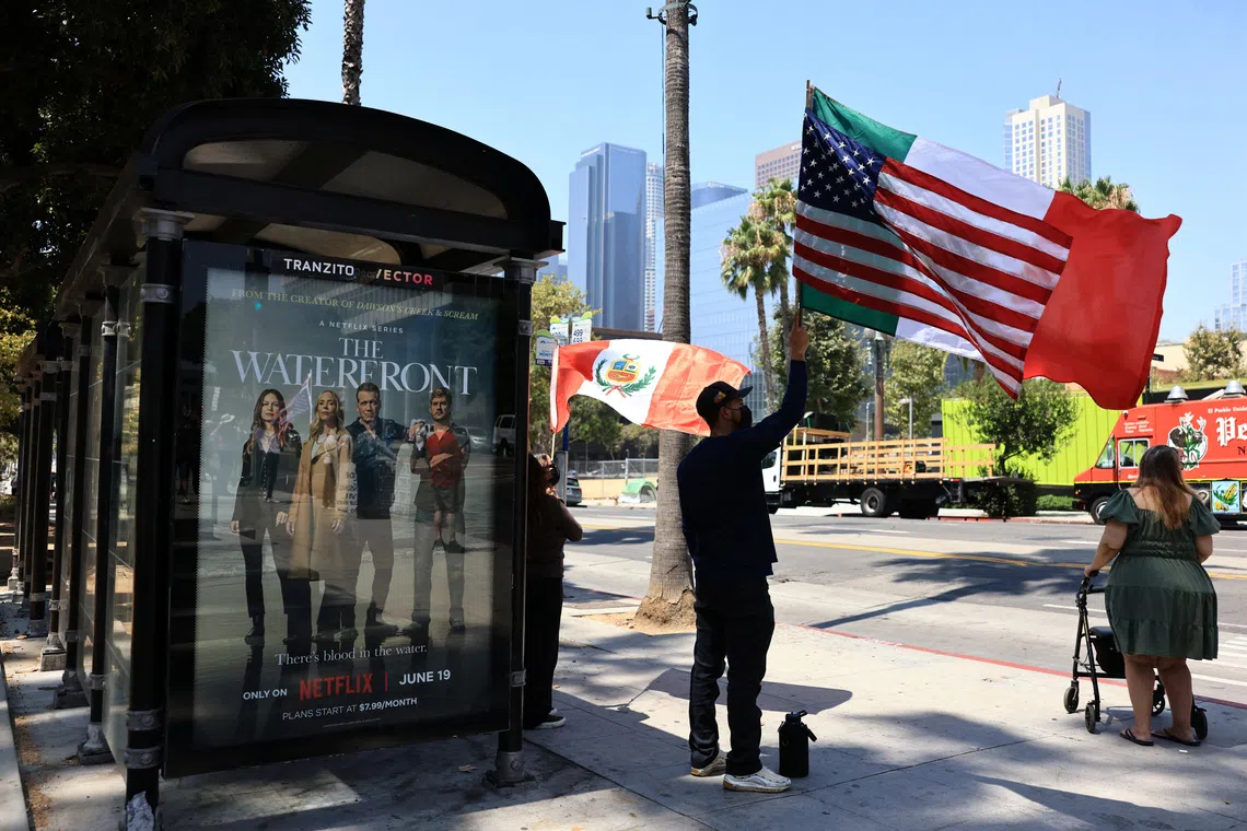A man holds flags during a protest against federal migration enforcement in downtown Los Angeles, California, U.S. August 2, 2025. REUTERS/David Swanson