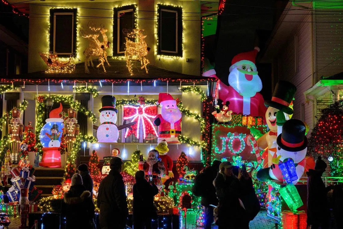 People look at homes decorated with Christmas lights and ornaments in the Dyker Heights neighborhood of New York City on Dec 8, 2022. 