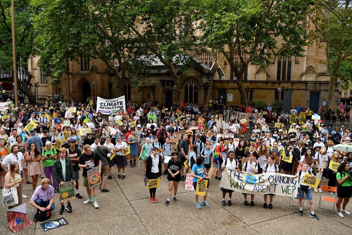 Protesters hold placards during a Global Climate Strike protest at Sydney Town Hall in Sydney, on March 3, 2023. 