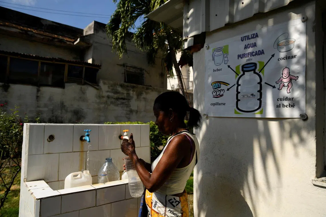A woman fills up bottles with water from a church group that offers residents small quantities of water to stem the shortage, in Havana, Cuba September 12, 2024. REUTERS/Norlys Perez
