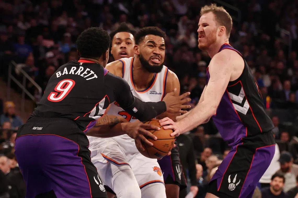 Karl-Anthony Towns of the New York Knicks is fouled by Jakob Poeltl and RJ Barrett of the Toronto Raptors during their game at Madison Square Garden.