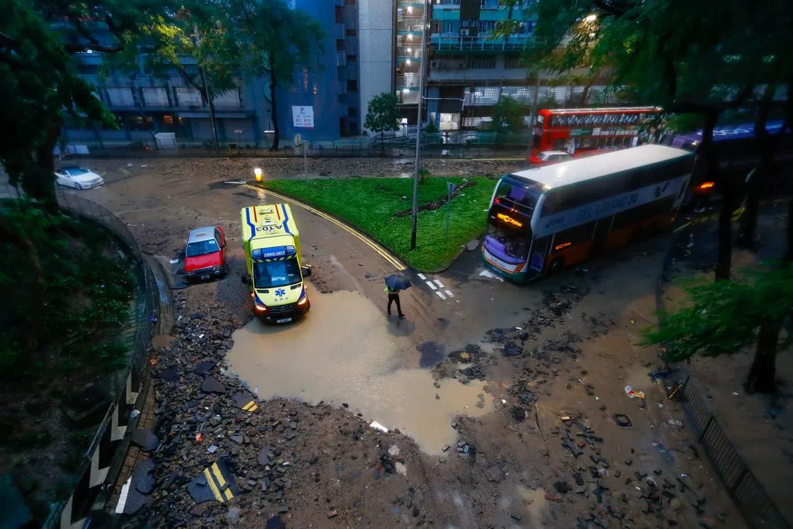 A man walking past damaged vehicles on a flooded road following continued torrential rains hitting the city, in Hong Kong, China, Sept 8, 2023. 