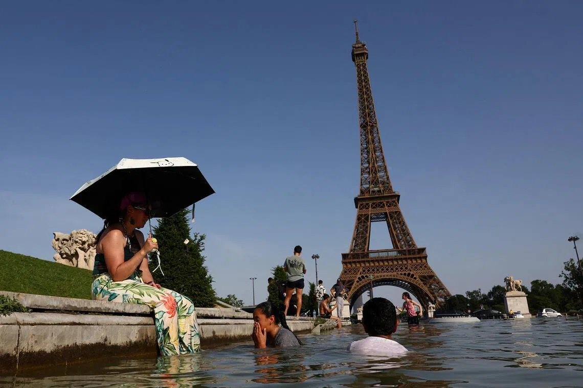 People cool off in the Trocadero fountain in front of the Eiffel Tower as temperatures rise in Paris during a heatwave.