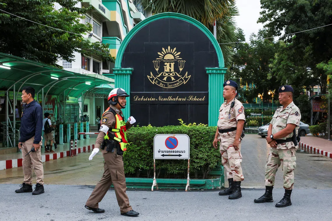 A police officer and civil defence volunteers stand guard at the entrance of Debsirin Nonthaburi School on Sept 1.