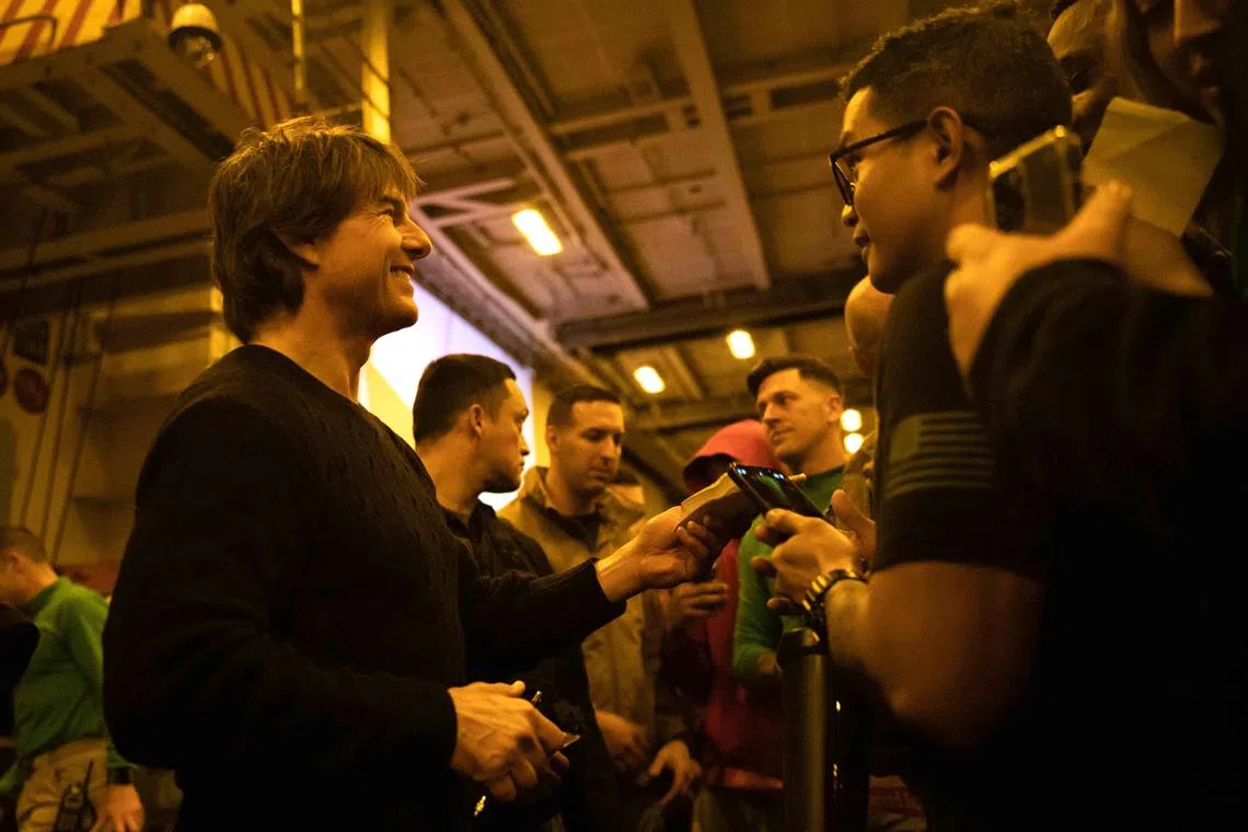 Tom Cruise (left) meets with sailors aboard the Nimitz-class aircraft carrier USS George H.W. Bush during a visit to the ship on March 2, 2023. 