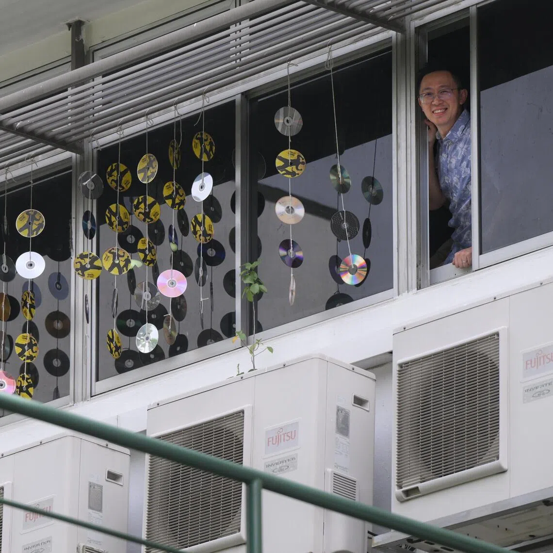 Jacob Tan, a senior biology teacher from Commonwealth Secondary School, seen with CDs hung outside the windows of the staff pantry at the school, where they have been installed to minimise bird strikes.