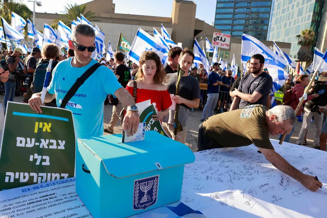 An Israeli military reservist drops a signed declaration in a box in Tel Aviv, announcing the suspension of his voluntary reserve duty, in protest at the government's judicial overhaul Bill.