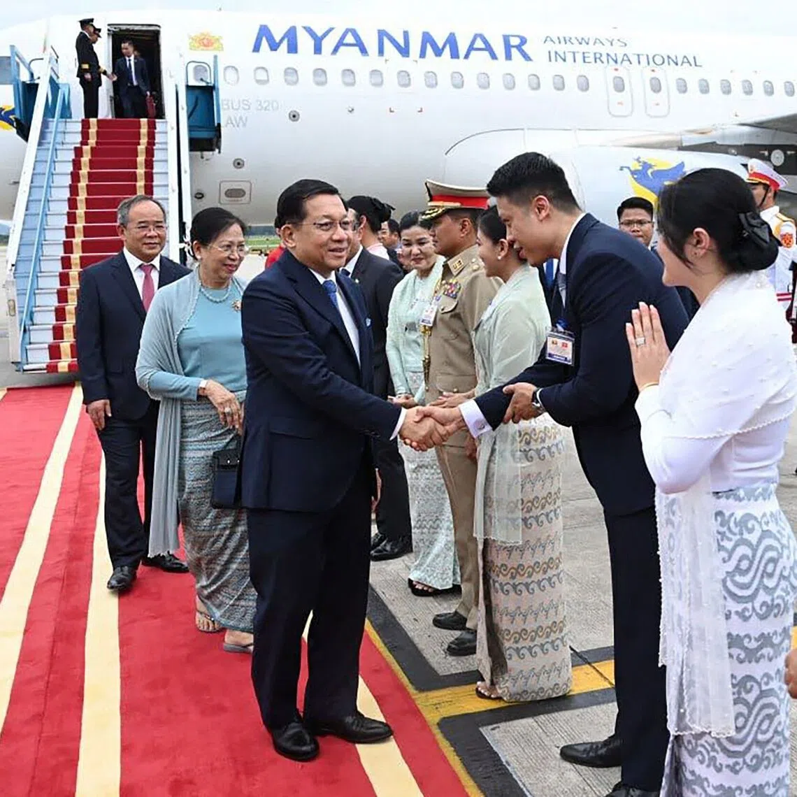 Myanmar’s President Min Aung Hlaing (centre) shaking hands with officials after arriving in Hanoi.