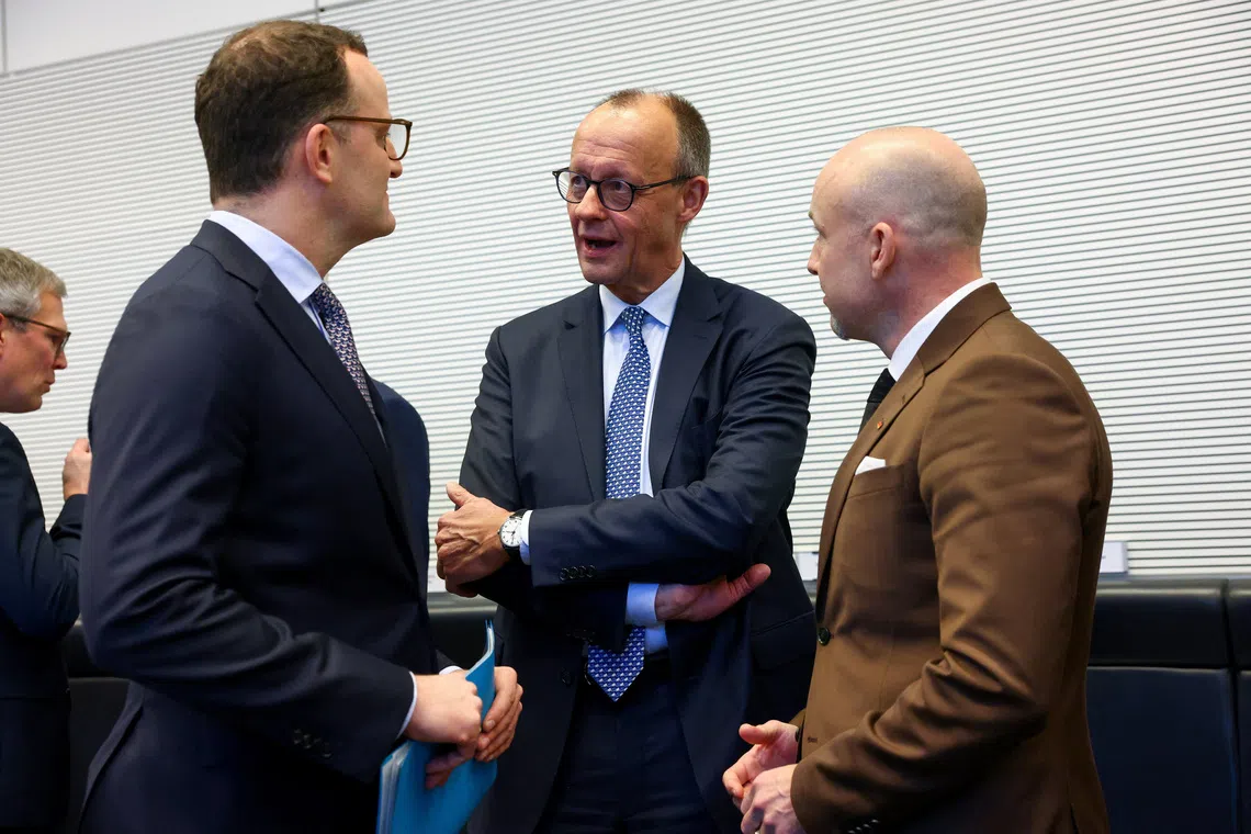 German Chancellor Friedrich Merz speaks to Christian Democratic Union's Jens Spahn, the CDU/CSU parliamentary group leader, and member of the German Bundestag Alexander Hoffmann on the day of a CDU/CSU fraction meeting in Berlin, Germany, December 2, 2025.   REUTERS/Christian Mang