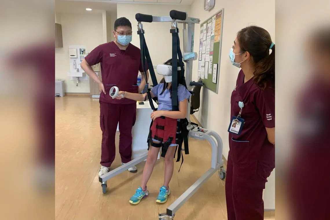 Sophie playing virtual-reality games as part of her therapy with Mr Derek Tan and Ms Jessica Law, senior physiotherapists at NUH, in November 2022.