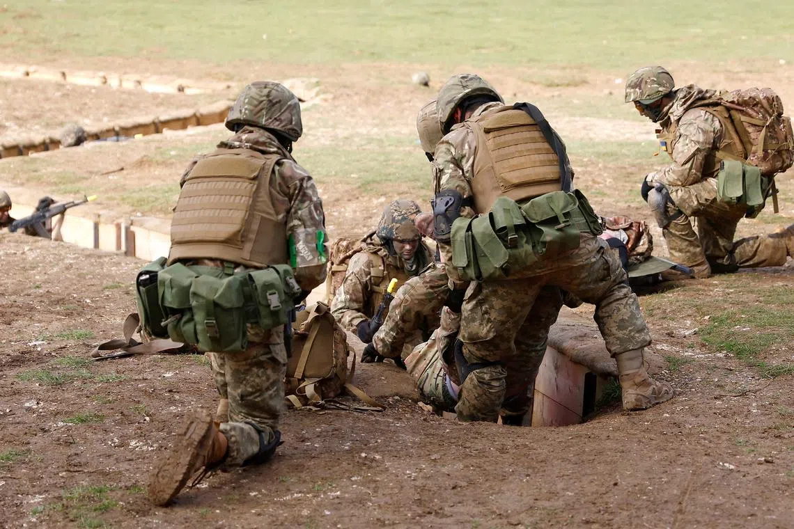 Ukrainian military recruits take part in a British army trench defence exercise, in southern Britain, on Feb 25.