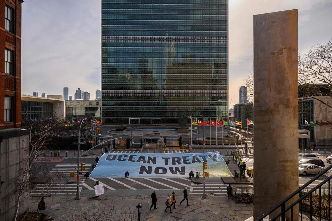 Activists from Greenpeace display a banner before the United Nations headquarters during ongoing negotiations at the UN on a treaty to protect the high seas in New York on February 27, 2023. (Photo by Ed JONES / AFP)
