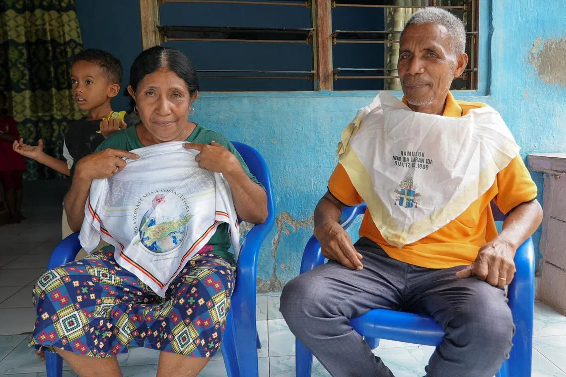 Pedro de Souza, 63, and his wife Zelia Soares, 63, show scarves they had when attending Masses led by Pope John Paul II in 1989 and Pope Francis in September last year, during an interview at their home in Dili, East Timor, April 23, 2025. REUTERS/Yuddy Cahya Budiman