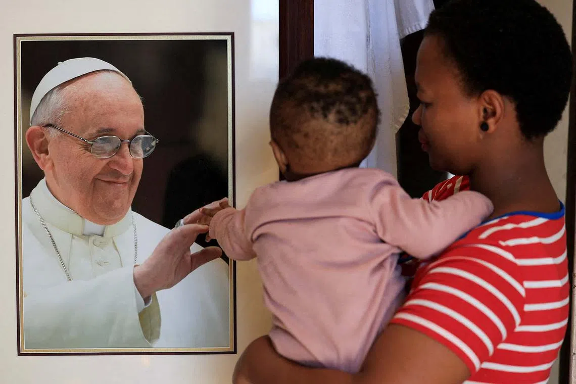 A child touching a photograph of late Pope Francis at a Memorial Mass at St Mary's Cathedral, in Cape Town, South Africa, April 23, 2025. 