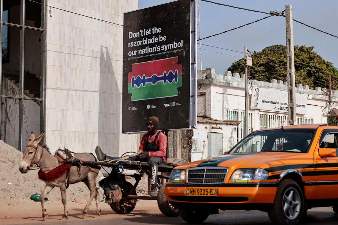 A man rides a cart past a poster advocating for an end to female genital mutilation (FGM), in Banjul, Gambia, June 6, 2024. REUTERS/Zohra Bensemra