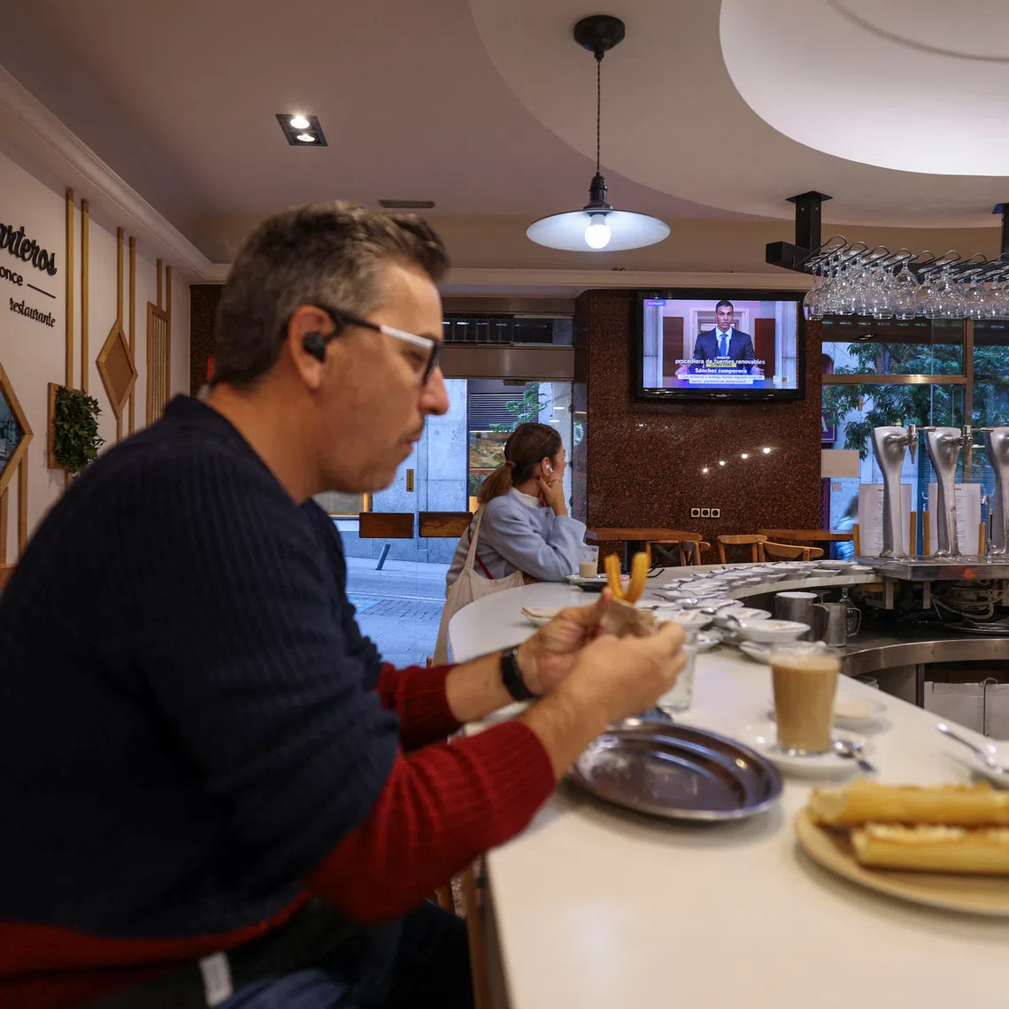 A person watches as Spain's Prime Minister Pedro Sanchez is seen on a screen, calling an early election for November 29, during a live news broadcast, at a bar in Madrid, Spain October 5, 2026. REUTERS/Juan Medina