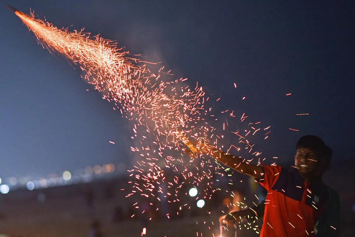 A boy lighting a firecracker on the occasion of Diwali, the Hindu festival of lights, in Chennai, India on Nov 12, 2023.
