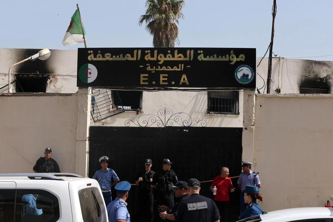 Police stand guard after a fire affected an orphanage in the Algiers suburb of Mohammadia, Algeria, on July 16.