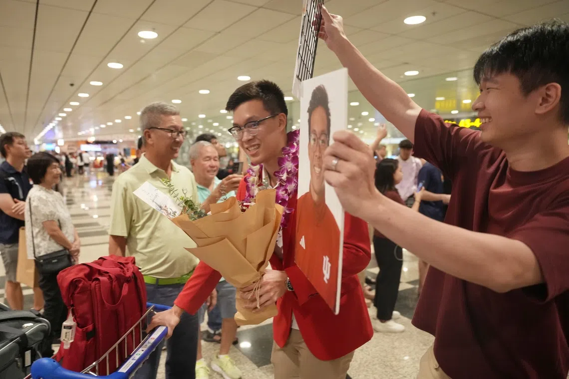Mikkel Lee, returning to Singapore with four golds from the 2025 SEA Games, being welcomed with a banner held aloft by his older brother.