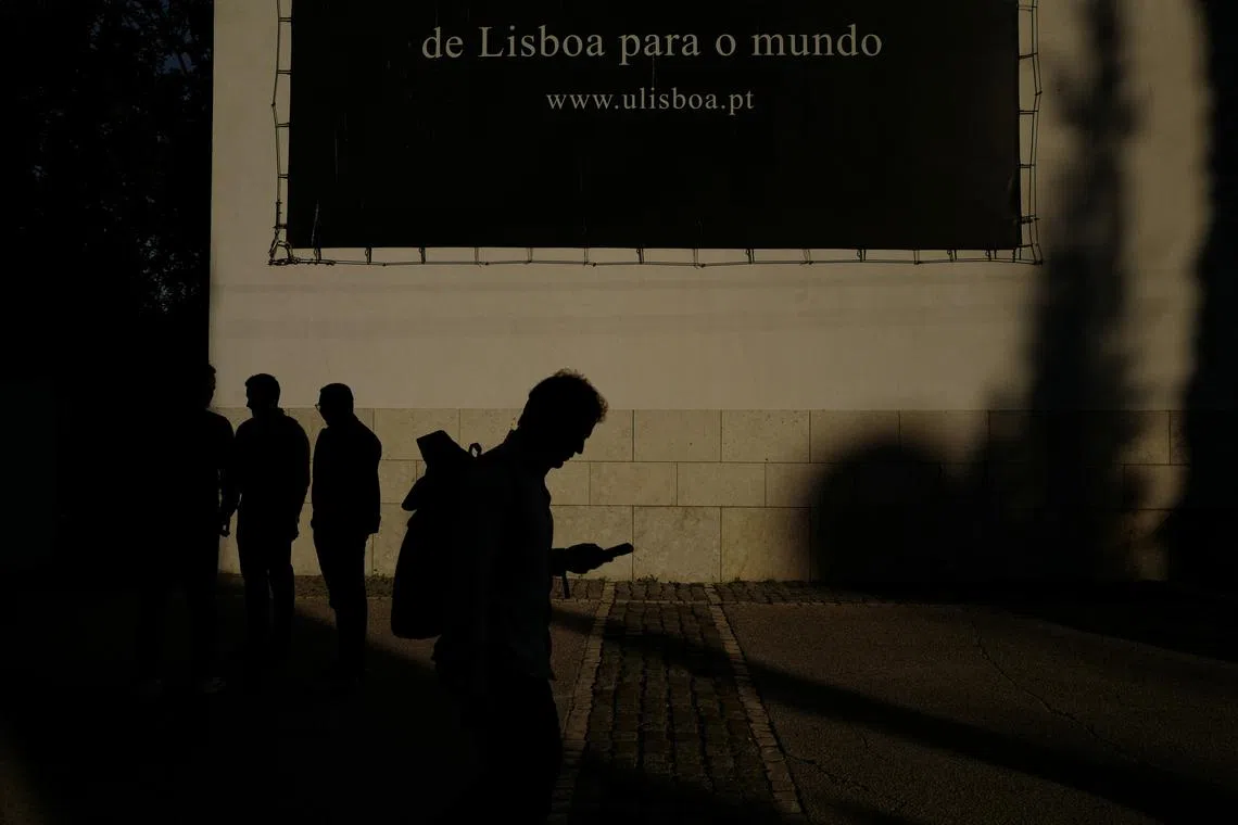 A silhouetted person passes by a banner of University of Lisbon that reads \"From Lisbon to the World\", in Lisbon, Portugal, November 12, 2024. REUTERS/Pedro Nunes