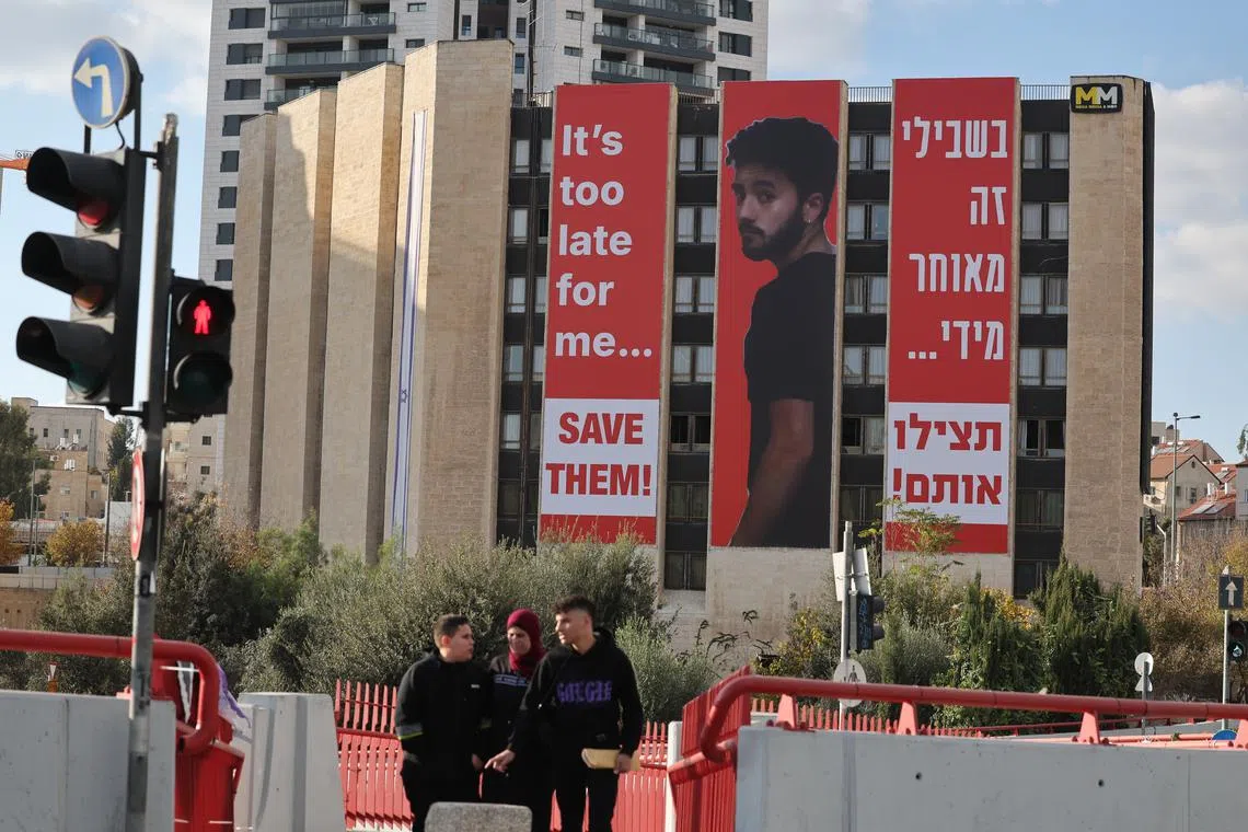 People walk past a large billboard showing an image of Israeli hostage Hersh Goldberg-Polin, who was killed in captivity.