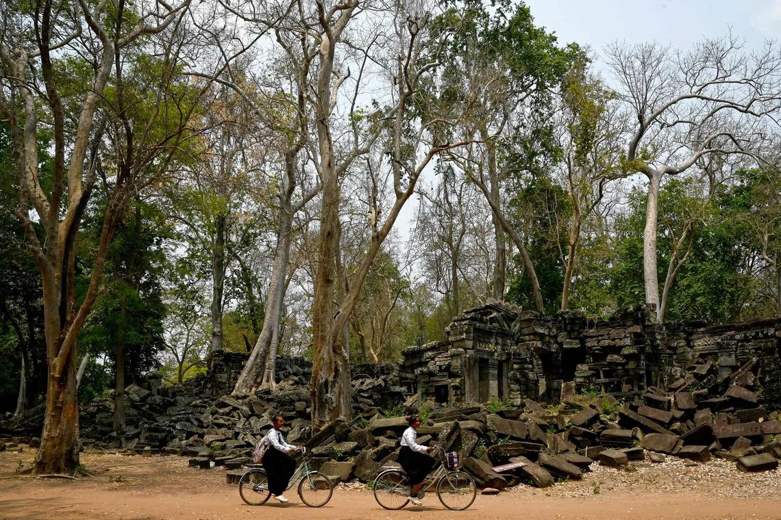 Cambodian pupils riding their bicycle past the Banteay Chhmar temple in the Banteay Meanchey province, on March 26, 2025.