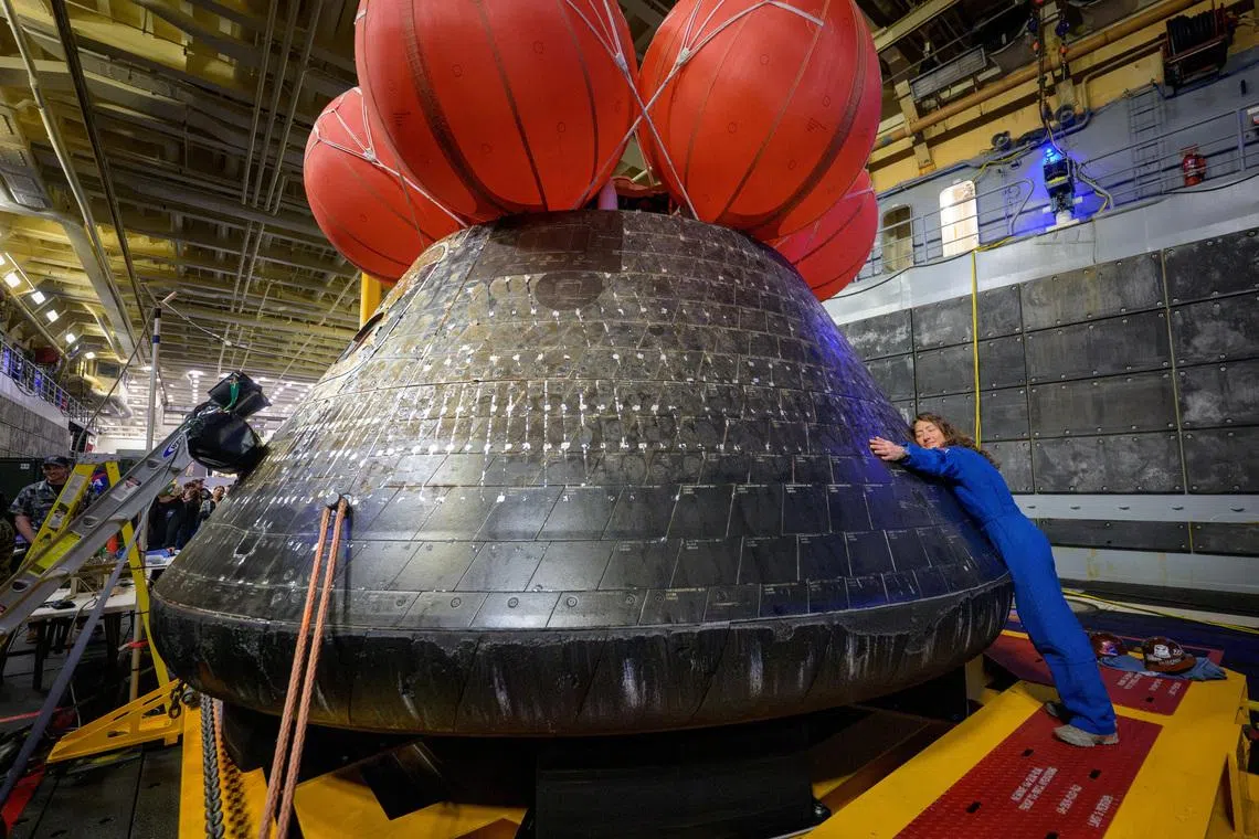 NASA astronaut Christina Koch hugs the Orion spacecraft in the well deck of the U.S. Navy ship USS John P. Murtha a day after her crew splashed down in the Pacific Ocean off the coast of California, U.S. April 11, 2026. NASA/Bill Ingalls/Handout via REUTERS THIS IMAGE HAS BEEN SUPPLIED BY A THIRD PARTY. MANDATORY CREDIT. TPX IMAGES OF THE DAY