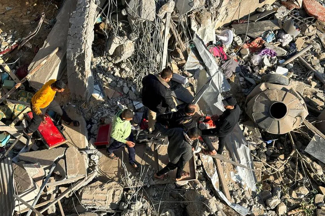 Palestinians gather at the site of an Israeli strike, amid the ongoing conflict between Israel and the Palestinian Islamist group Hamas, in Rafah, in the southern Gaza Strip, December 4, 2023. REUTERS/Fadi Shana