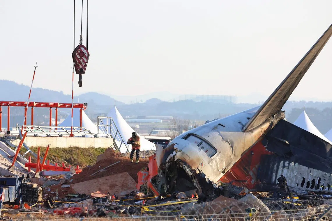 A firefighter takes pictures of the debris at the scene of the Jeju Air passenger plane crash at Muan International Airport on Jan 3, 2025. 