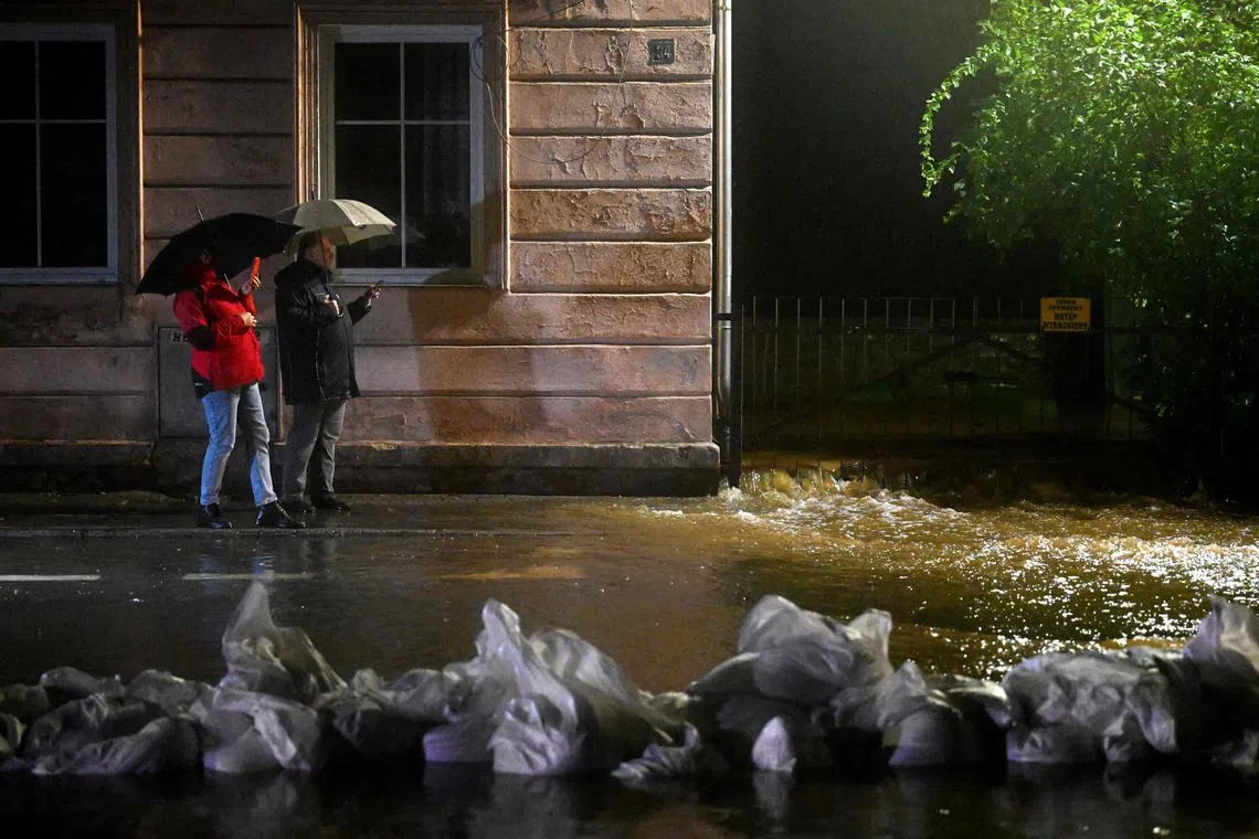 Local residents take photos on their mobile phones as water from the Biala river come to the city center in southern Poland as Central Europe faces heavy rainfall expected to cause floods. 