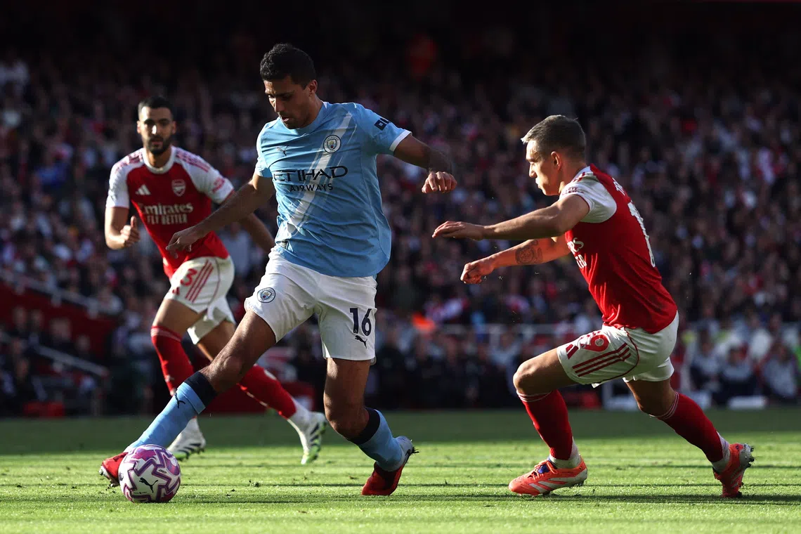Soccer Football - Premier League - Arsenal v Manchester City - Emirates Stadium, London, Britain - September 21, 2025 Manchester City's Rodri in action with Arsenal's Leandro Trossard REUTERS/Hannah Mckay