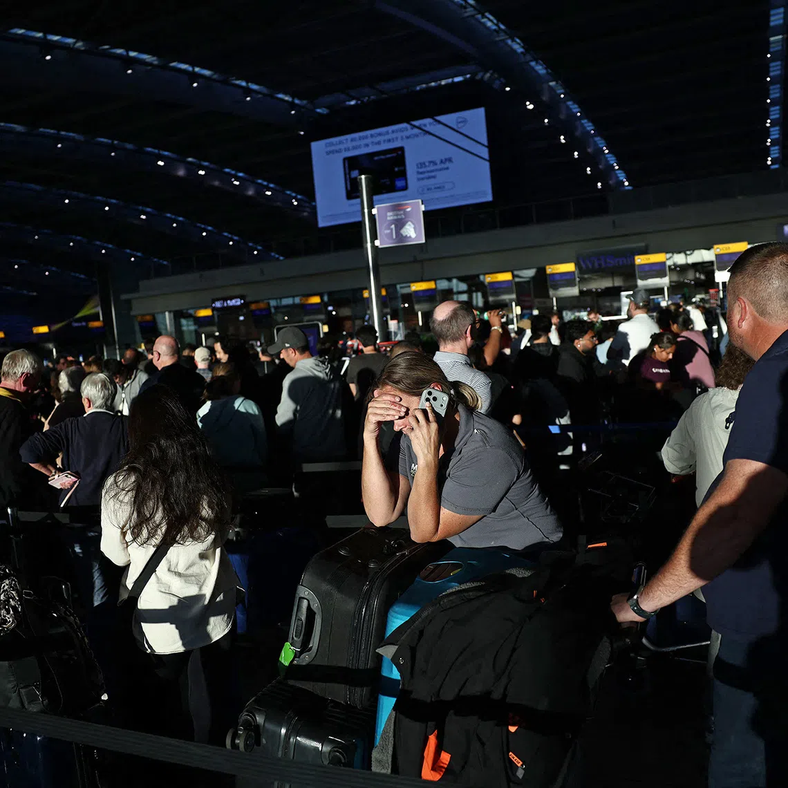 People stand with their luggage as the queue at check-in desks inside Terminal 5 of London Heathrow airport, west of London on September 8, 2026, following major disruption due an issue affecting the NATS air traffic control systems. More than 400 flights to and from UK airports were cancelled on September 8 due to what the country's air traffic control service said was a "technical issue", in the latest glitch to cause disruption. (Photo by Henry NICHOLLS / AFP)